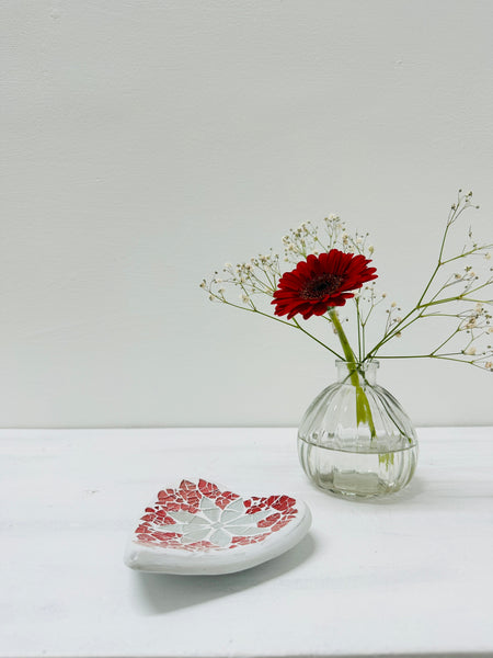 display view of heart bowl with a flower in a vase in the background 