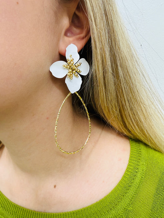 A pair of white floral earrings with a golden drop design.