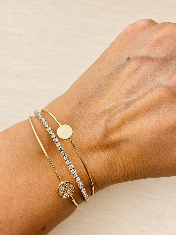 Close-up of a wrist wearing gold bracelets with a light background