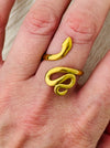 Gold-tone adjustable snake ring with sleek wrap-around design, displayed on a model.