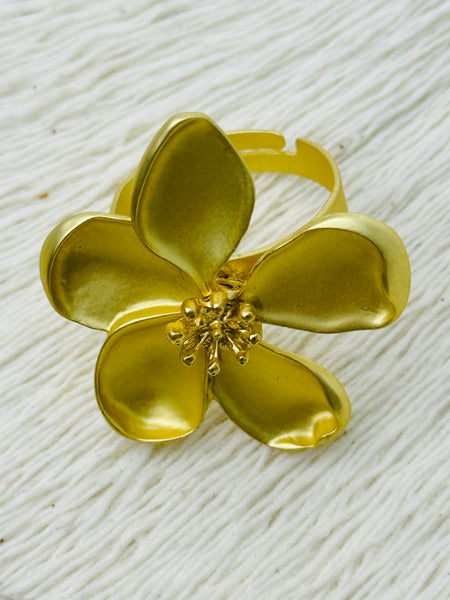 Adjustable statement ring with matte gold-tone five-petal flower and textured centre, displayed on a white background.