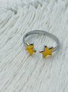 Twin star adjustable ring with two gold-tone stars on a silver-tone open band, displayed on a white fabric background.
