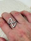 Minimalist abstract open band ring in polished silver tone with adjustable fit, displayed on a model.
