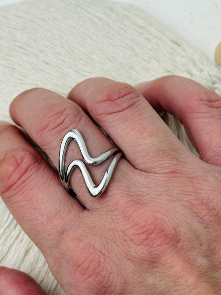 Minimalist abstract open band ring in polished silver tone with adjustable fit, displayed on a model.
