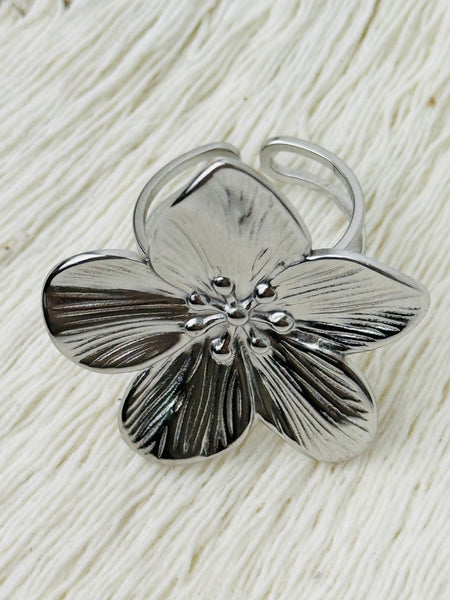 Adjustable silver-tone statement ring featuring a five-petal flower with textured detail, displayed on a white background.