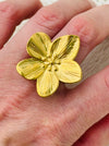Adjustable silver-tone statement ring featuring a five-petal flower with textured detail, displayed on a model.