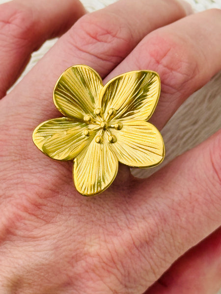 Adjustable silver-tone statement ring featuring a five-petal flower with textured detail, displayed on a model.