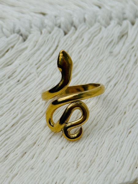 Gold-tone adjustable snake ring with sleek wrap-around design, displayed on a white fabric background.
