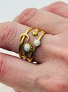 Gold celestial harmony ring with crescent moon, star, sun and moonstone-effect cabochons on an open band, displayed on a model.