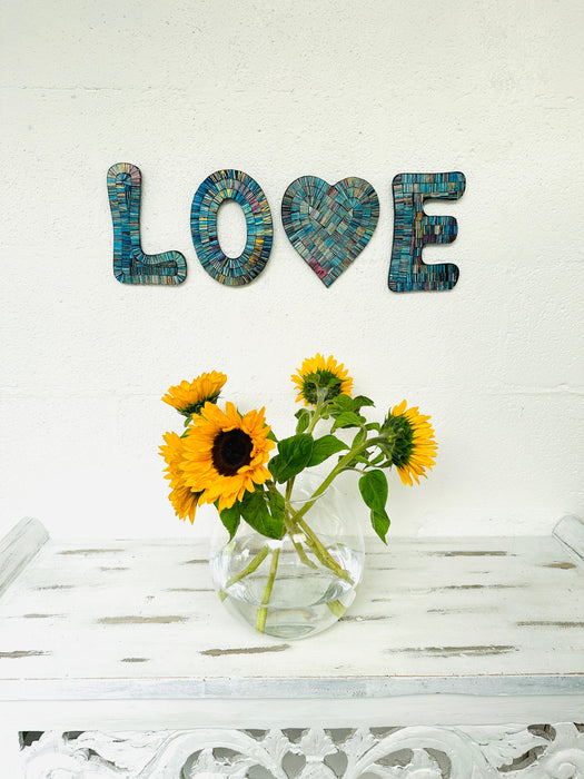 display view of love mosaic wall art on the wall with vase of flowers on table below
