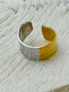 Bi-tone open band ring with textured silver and gold finish on a soft fabric background.