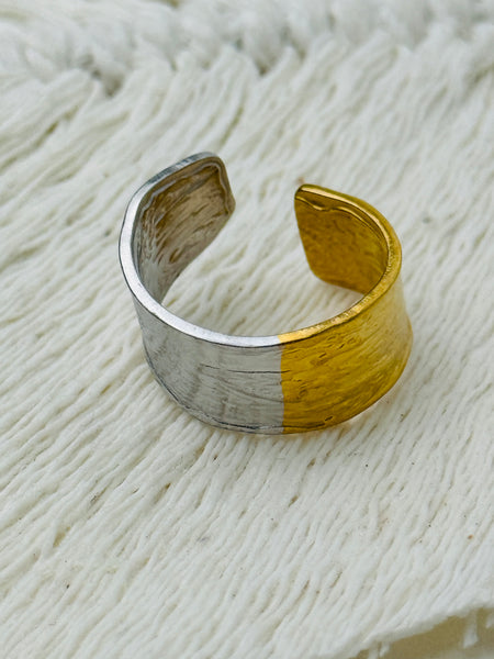 Bi-tone open band ring with textured silver and gold finish on a soft fabric background.