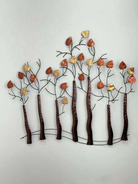 Decorative wall art with metal branches and leaves on a white background