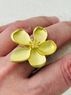 Adjustable statement ring with matte gold-tone five-petal flower and textured centre, displayed on a model.