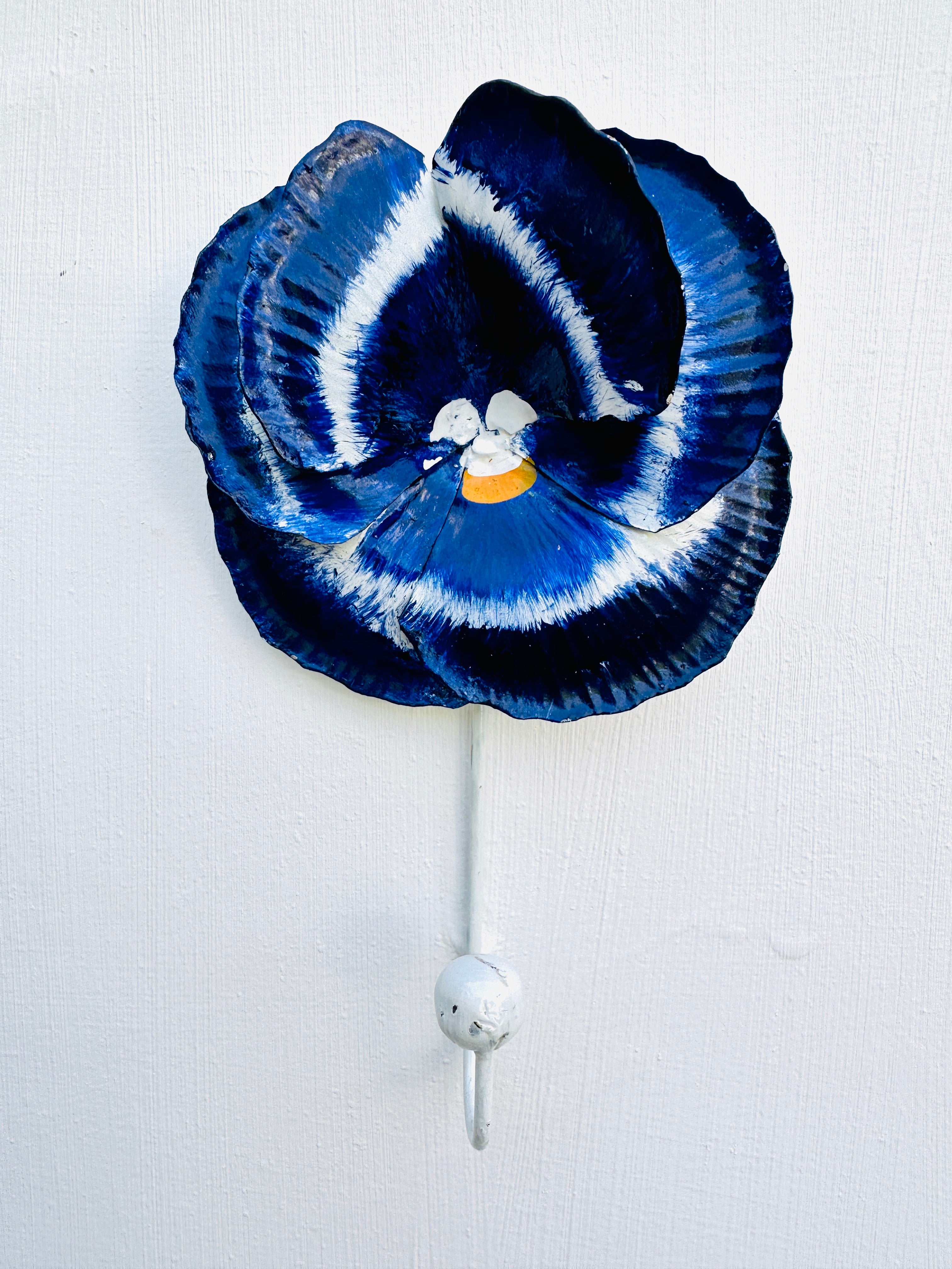 front view of metal pansy hook in blue attached on wall
