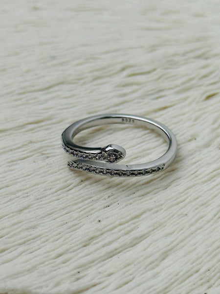 Delicate silver sleek snake ring with fine pave-style detailing and adjustable open band, displayed on a white fabric background.