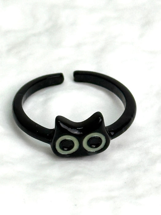 Black cat-shaped ring with glowing eyes on a white background