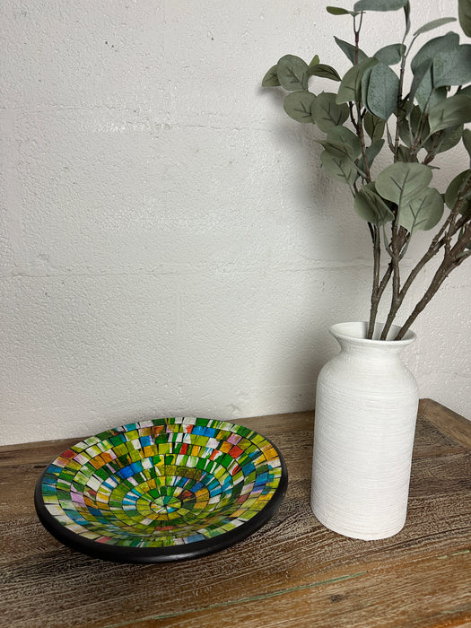 display view of mosaic glass bowl next to a vase of leaves