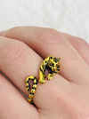 Gold tiger-shaped ring on a finger against a white background