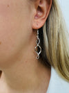 Elegant silver-tone twist earrings with a modern spiral design, displayed on a model.