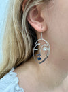 close-up of silver-coloured abstract portrait dangle earring