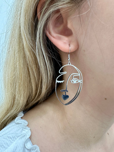 close-up of silver-coloured abstract portrait dangle earring