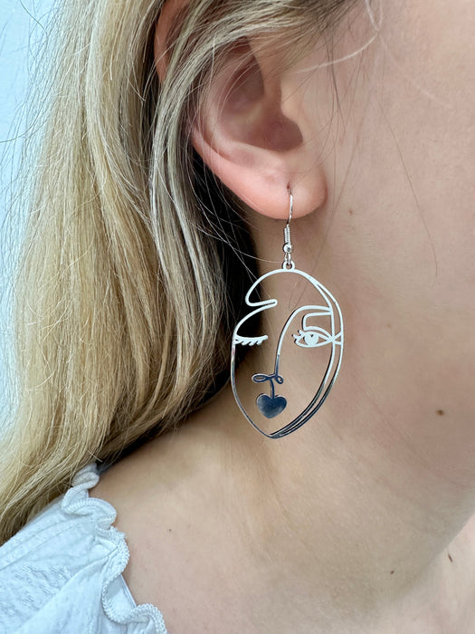 close-up of silver-coloured abstract portrait dangle earring