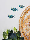 Aqua metal fish wall art displayed beside indoor plants and decorative elements