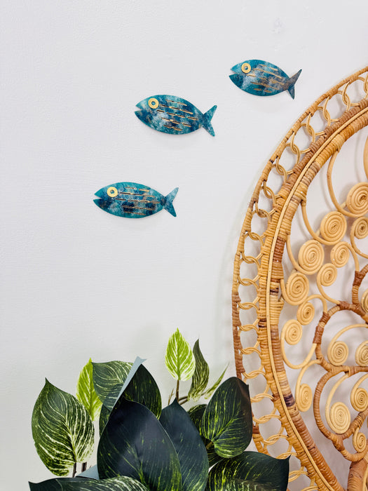 Aqua metal fish wall art displayed beside indoor plants and decorative elements