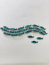 Display view of 18-piece aqua striped metal fish shoal wall art with 3 single fish on a white surface