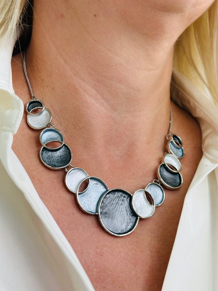 Model wearing the Aurea statement necklace with white and grey circular design.
