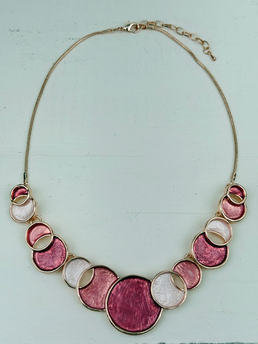 Aurea enamel necklace with rose-gold circular design in a celestial-inspired style.