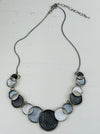 Necklace with circular design in white and grey tones on a white background