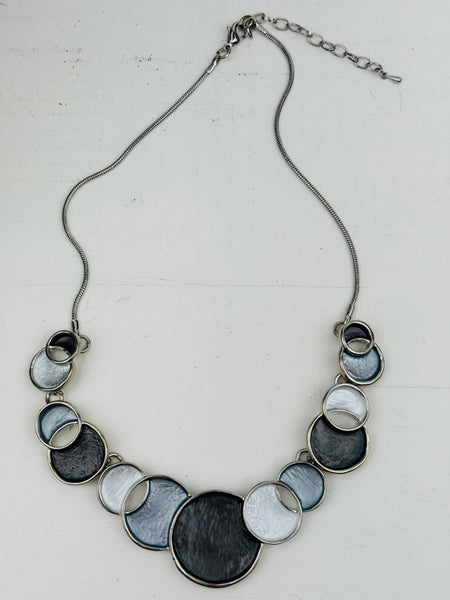 Necklace with circular design in white and grey tones on a white background