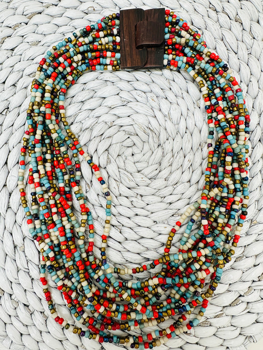 Bead statement waterfall style necklace with multicoloured seed beads and hand carved wood clasp., displayed on a white background.