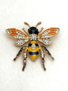 Decorative bee brooch with gold, black, and yellow colors on a white background