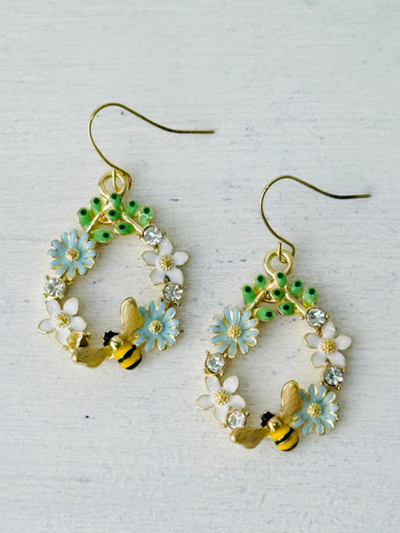 Bee and daisy, floral dangle earrings with enamel flowers, sparkling rhinestones, and gold-tone bee detail, displayed on a white background.