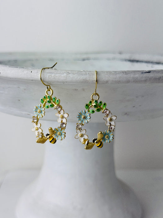 Bee and daisy, floral dangle earrings with enamel flowers, sparkling rhinestones, and gold-tone bee detail, displayed on a white background.