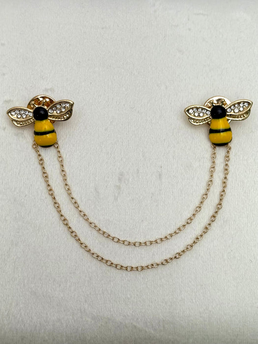 gold tone bee-shaped lapel pin with chain and crystal details on a white background