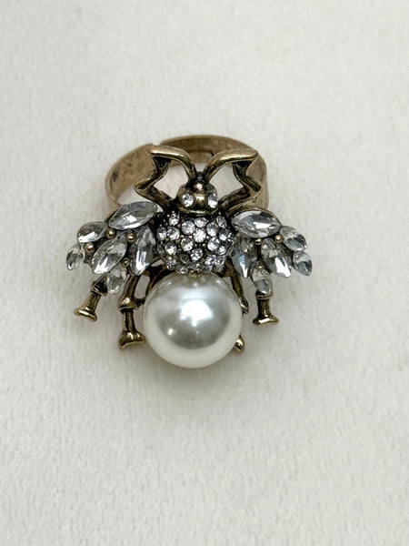 Decorative bee statement ring with pearl and crystal accents on a white background