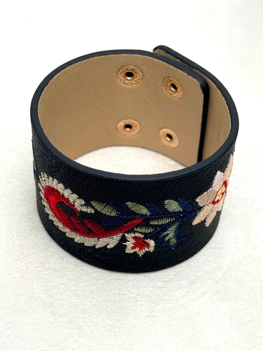 black faux leather cuff with floral embroidery on a white background