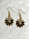Pair of floral earrings with black and gold details on a white background