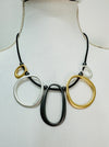 close-up of black faux leather necklace with mixed-metal oval links in gold, silver and dark grey tones.