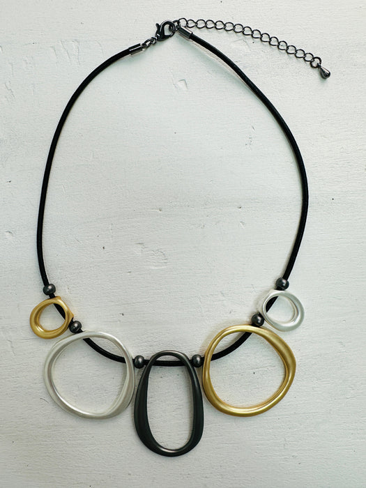 front-of black faux leather necklace with mixed-metal oval links in gold, silver and dark grey tones.