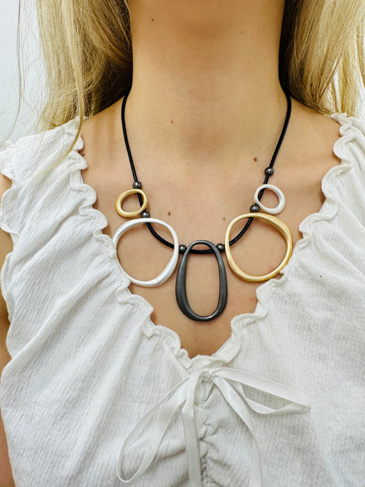  black faux leather necklace with mixed-metal oval links in gold, silver and dark grey tones displayed on a model