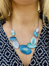 Blue and aqua enamel geometric statement necklace with silver tone chain and textured oval accents displayed on a model.