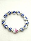 Blue and white porcelain bead stretch bracelet with pink floral centre bead and silver spacers on a white background