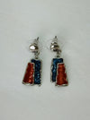 Gunmetal and bronze rectangular enamel drop earrings with a silver-tone outline, displayed on a table.