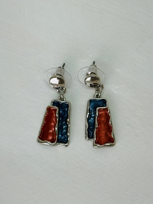Gunmetal and bronze rectangular enamel drop earrings with a silver-tone outline, displayed on a table.