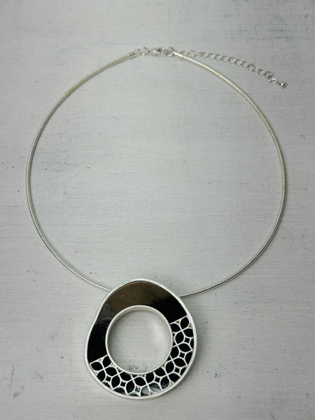 Dark brown enamel circle pendant necklace dispayed on a table